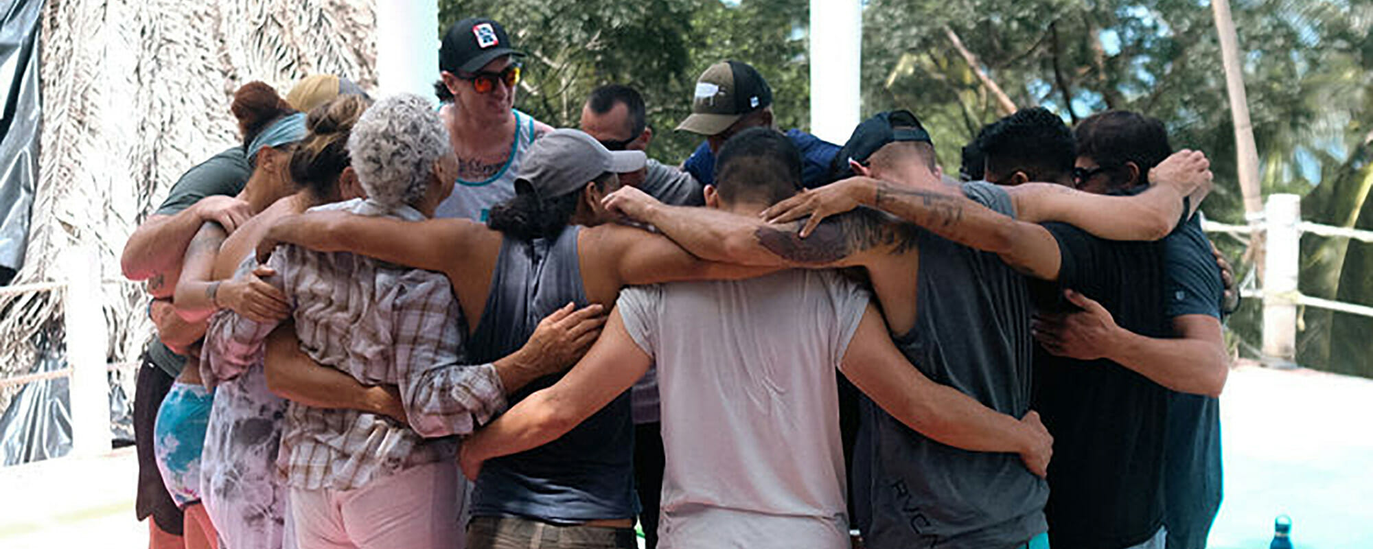 Group of retreat attendees standing in a circle with their arms around each other