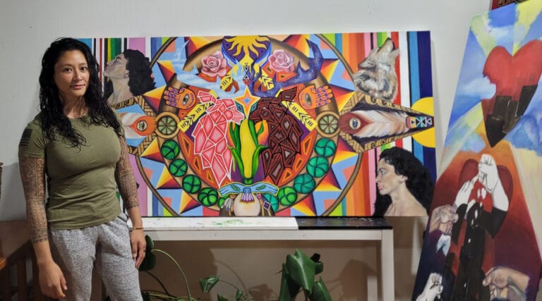 Artist Sam Juan posing next to painting titled "Self Love"